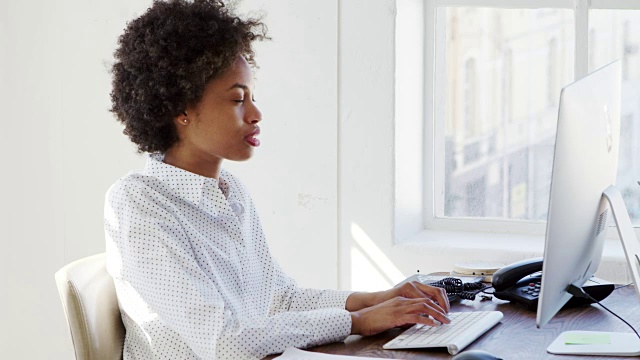 年轻的黑人女性在办公室里用电脑工作，特写视频素材