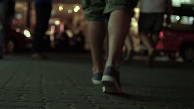 年轻人的双脚在人行道上走得很近。一个人的腿在泰国街道上移动的慢动作镜头视频素材
