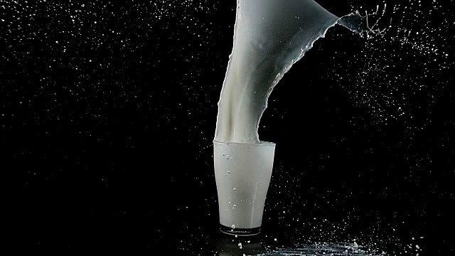 牛奶的玻璃在黑色背景下爆炸，慢镜头4K视频下载