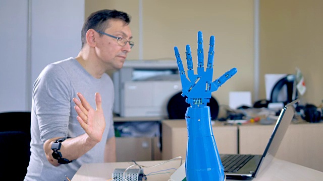 一位工程师正在测试一只蓝色的机械手。视频素材