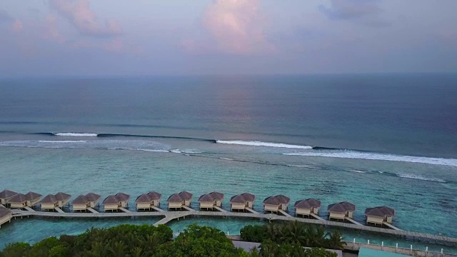 鸟瞰图的热带岛屿度假酒店与平房和蓝绿色的印度洋海浪在马尔代夫在4k视频素材
