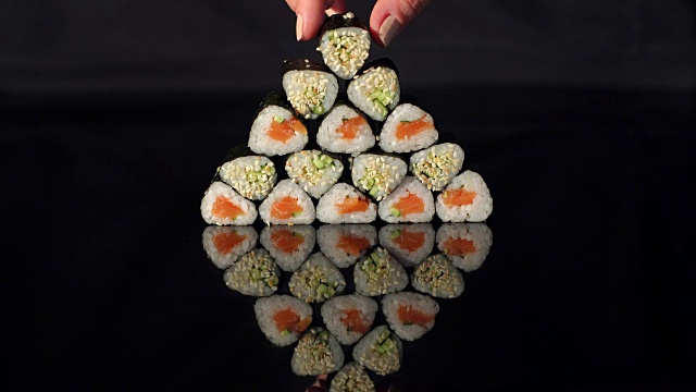 手把寿司放在黑色的金字塔上。视频素材