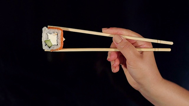 手拿筷子和寿司在黑色的背景视频素材