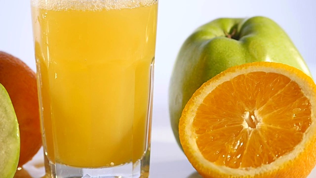 橙汁倒在彩色背景的玻璃上视频下载