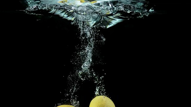 黄色柠檬，柑橘柠檬，水果落入水中的黑色背景，4K慢镜头视频素材