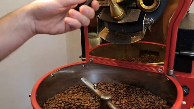 从烘培机的桶里倒出热烘培的咖啡豆。咖啡蒸汽视频素材