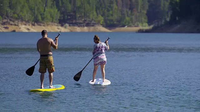 一对夫妇在湖上站立式划桨板视频素材