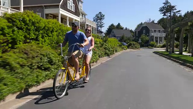 一对夫妇在沿海社区骑双人自行车视频下载