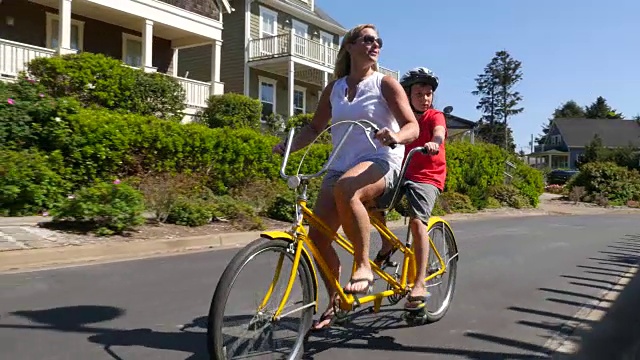 母亲和儿子在沿海社区骑双人自行车视频下载