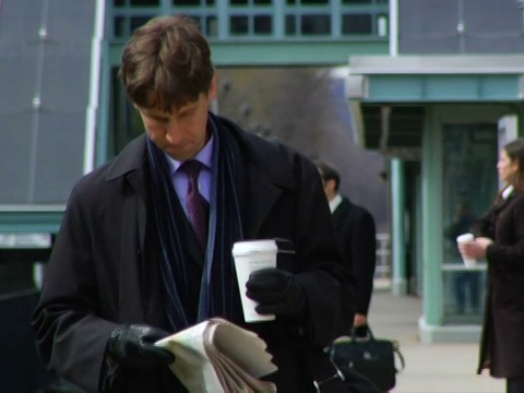 美国纽约州查帕奎，一名男子手持一次性杯子在火车站站台上看报纸视频素材