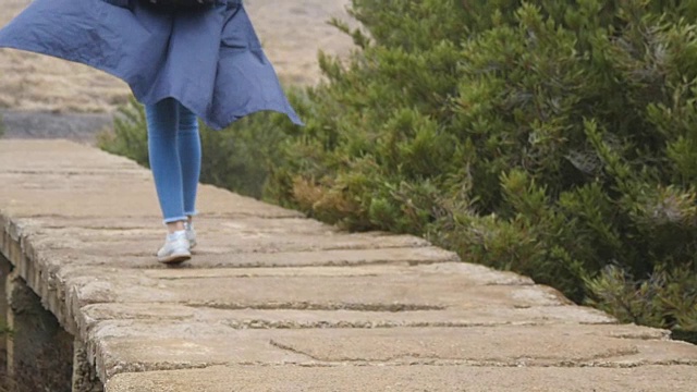年轻女性游客背包行走在户外的石头小径。女人的腿在美丽的自然岩石地上行走。女孩在旅行中踏山。健康的生活方式。慢动作视频素材