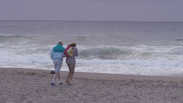 一对老年夫妇一起在海滩上散步视频素材