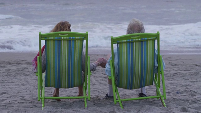 一对老年夫妇坐在海滩的椅子上视频素材