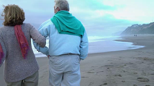老年夫妇一起在海滩上散步，脚的特写镜头视频素材
