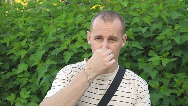 一名男子用手做出难闻气味的手势，用手捂住鼻子，表现出恶心的样子视频下载
