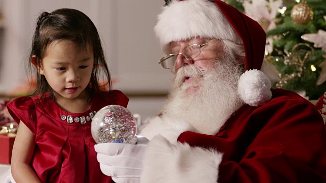 圣诞老人给小女孩看一个雪花玻璃球视频素材