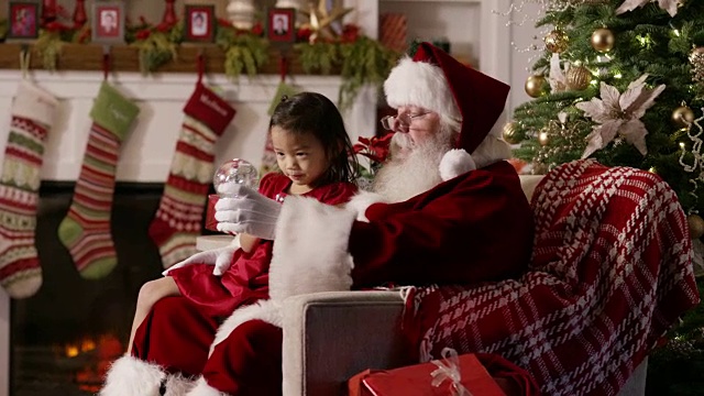 圣诞老人给小女孩看一个雪花玻璃球视频素材