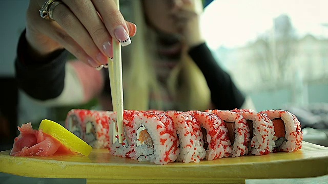 特写小女孩吃寿司用筷子在一家餐厅视频素材