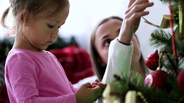妈妈和女儿在家里装饰圣诞树。视频素材