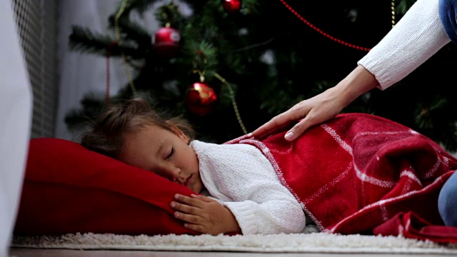 圣诞节前夕，妈妈来了，裹着红格子的婴儿睡在地板上。视频素材