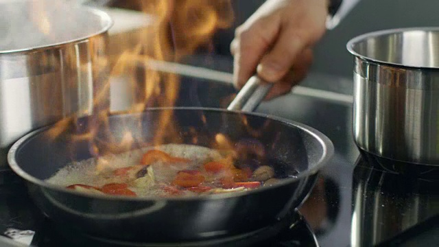 厨师在平底锅上准备火焰风格的菜肴的特写。油和酒精用明火点燃。视频素材
