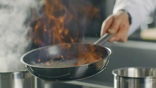 厨师在平底锅上准备火焰风格的菜肴的特写。油和酒精用明火点燃。视频素材