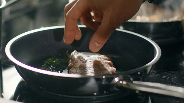 一个专业厨师把肉放在热锅上的特写。视频素材