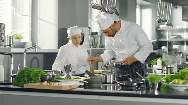 名厨和他的女学徒在现代五星级餐厅的厨房里准备特色菜。视频素材