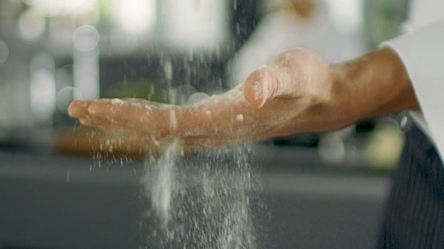 著名餐厅的面包师在现代化的厨房里用手筛面粉。视频素材