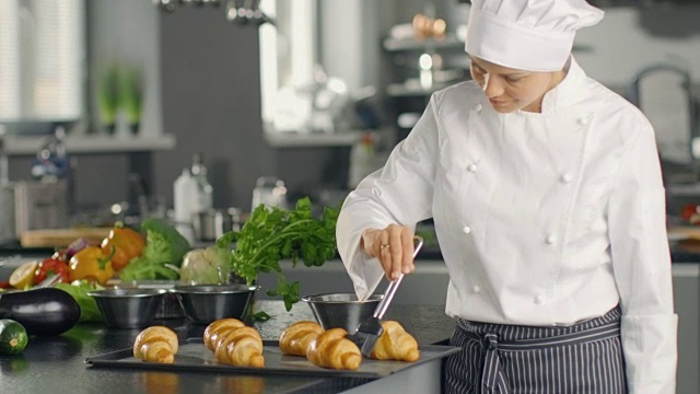 女厨师黄油牛角面包与油。视频素材