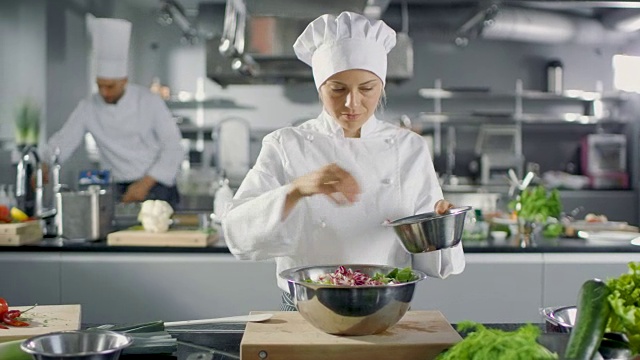 在一家著名的餐厅，女厨师正在准备沙拉。她在一家现代化的大厨房工作。视频下载