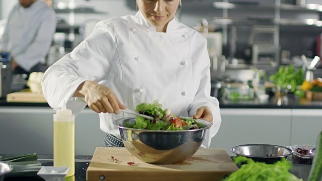 在一家著名的餐厅，女厨师正在准备沙拉。她在一家现代化的大厨房工作。视频素材