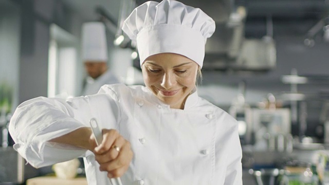 在一家著名的餐厅里，女厨师在做饭。她在一家现代化的大厨房工作。视频素材