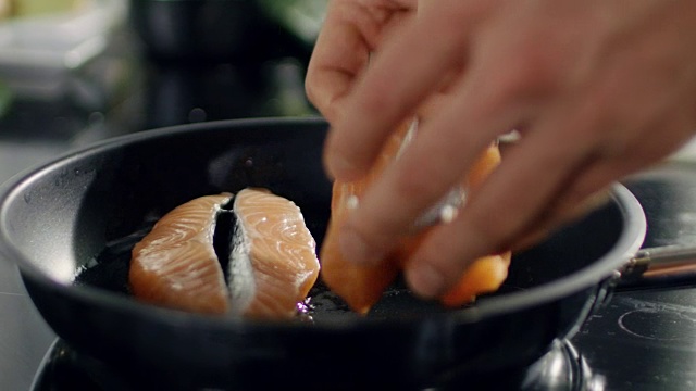 手把一块红色的鱼片放在热锅上的特写。视频下载