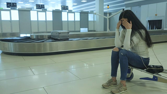 英俊的女士在机场等她的行李视频素材