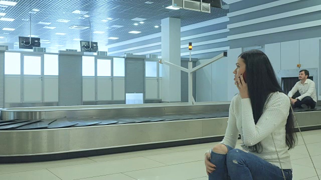 一位年轻女士在行李传送带接她的朋友视频素材