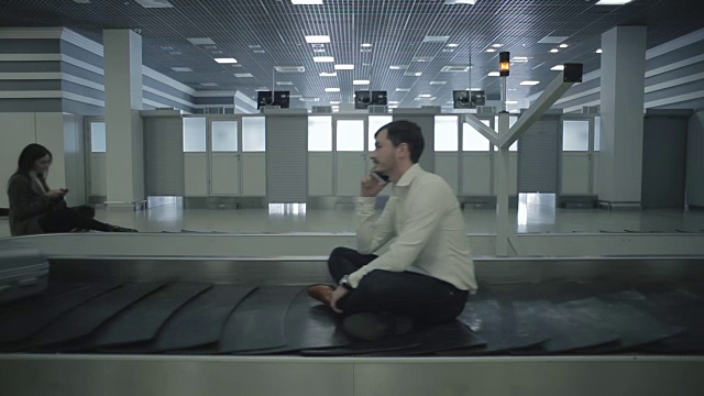 年轻人坐在机场的传送带上视频素材