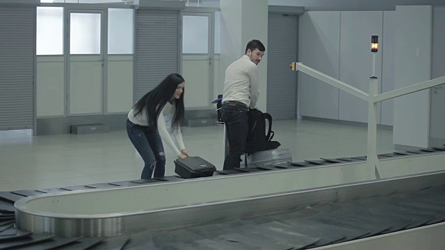一对年轻夫妇从机场的传送带上拿出行李视频素材