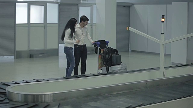年轻的女人和男人把他们的行李放到了手推车上视频素材