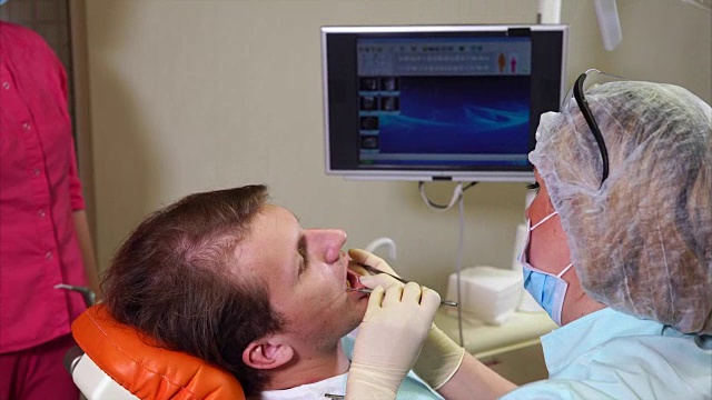 女牙医在屏幕上向男病人展示他的x光扫描图视频素材