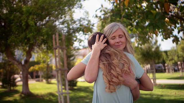 美丽的奶奶在绿色的花园里拥抱着孙女视频素材