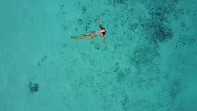 鸟瞰图一个迷人的女人在比基尼漂浮在水晶清澈的海洋。一个美丽的女孩在印度洋游泳视频下载