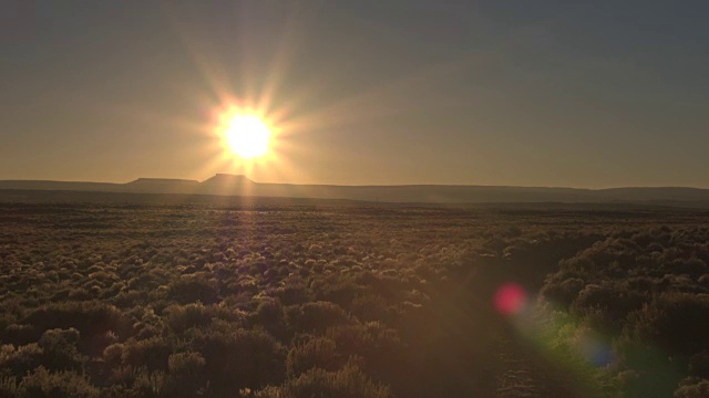 镜头:黑色SUV在金色的日出中穿过广袤的沙漠。视频素材