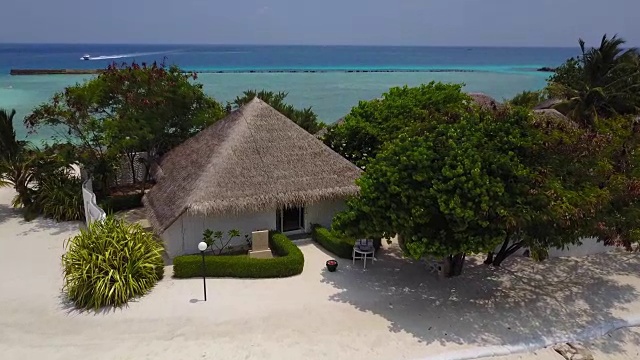 鸟瞰图的热带岛屿度假酒店水疗平房与白色沙滩，棕榈树和绿松石印度洋上的马尔代夫在4k。无人机摄像头接近平房视频素材