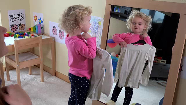 小女孩在镜子前量衣服视频素材