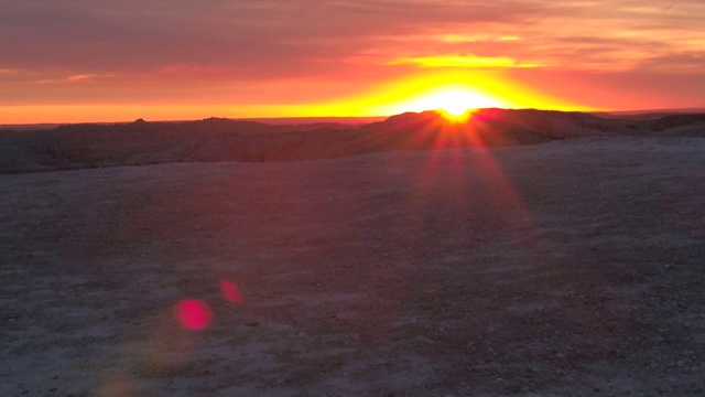 AERIAL: Badlands公园砂岩山背后令人惊叹的红色日落视频下载