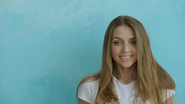 年轻的微笑和大笑的女人的特写镜头在蓝色的背景视频素材