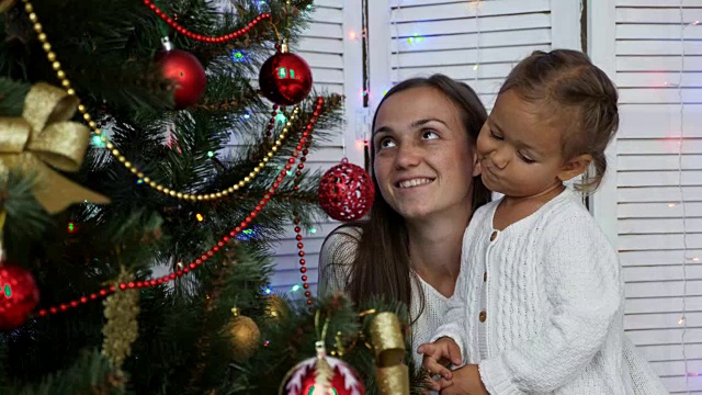 快乐的女孩们，妈妈和女儿在家里装饰圣诞树。视频素材