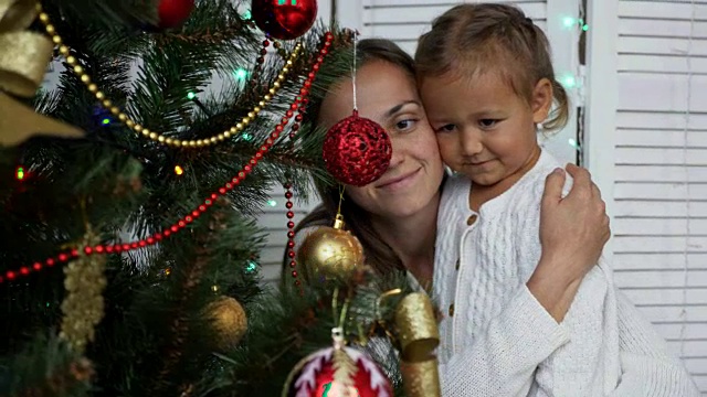 快乐的女孩们，妈妈和女儿在家里装饰圣诞树。视频素材