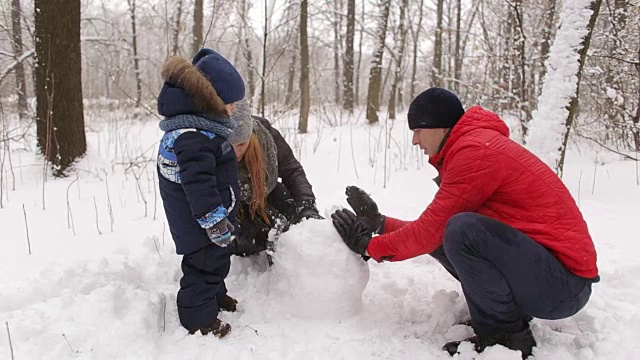 一家人和孩子们在公园堆雪人。视频素材
